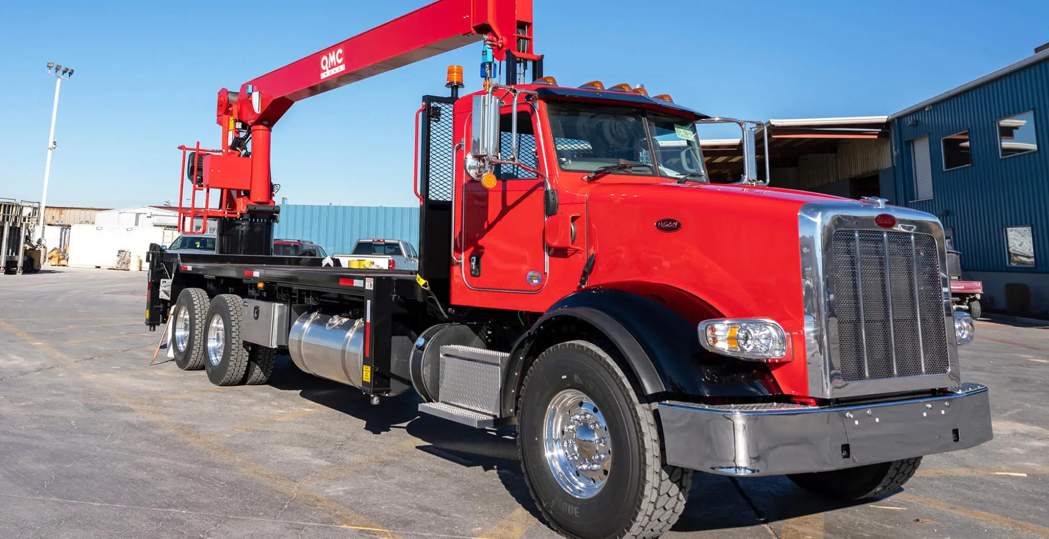 Red QMC 4037R rear-mounted boom truck crane with a 37' boom and three axles, representing medium-lift boom truck cranes engineered for versatility and performance.